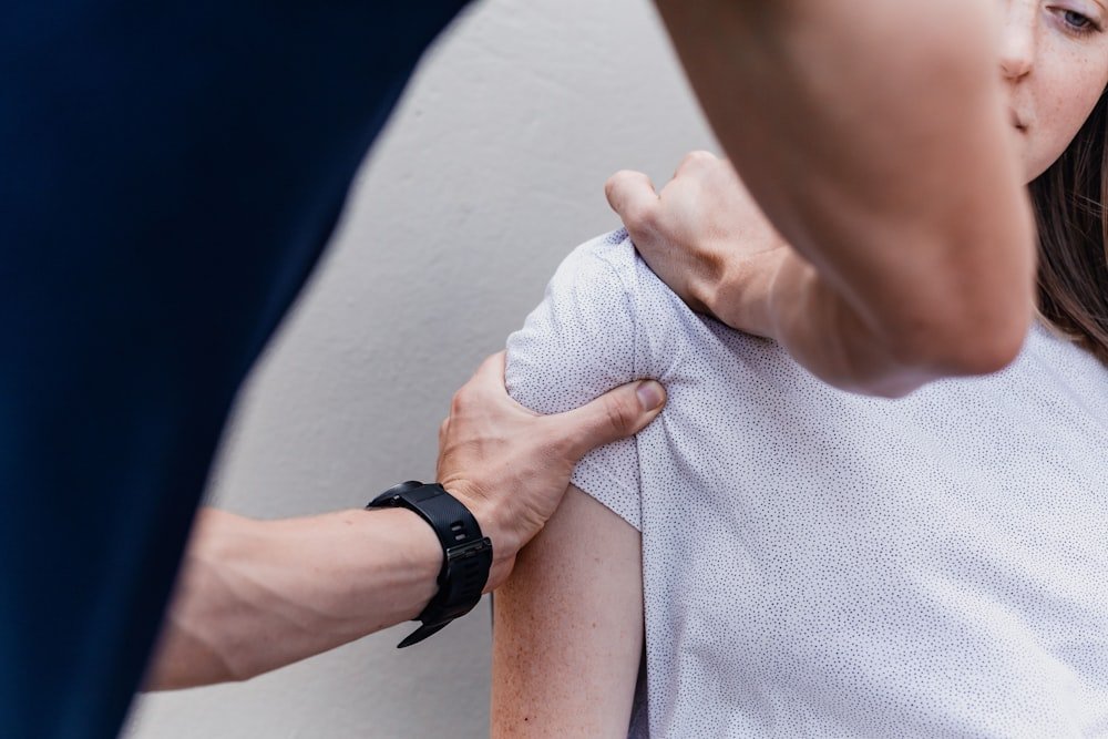 Fisioterapeuta apoiando o braço de um paciente durante sessão de terapia manual